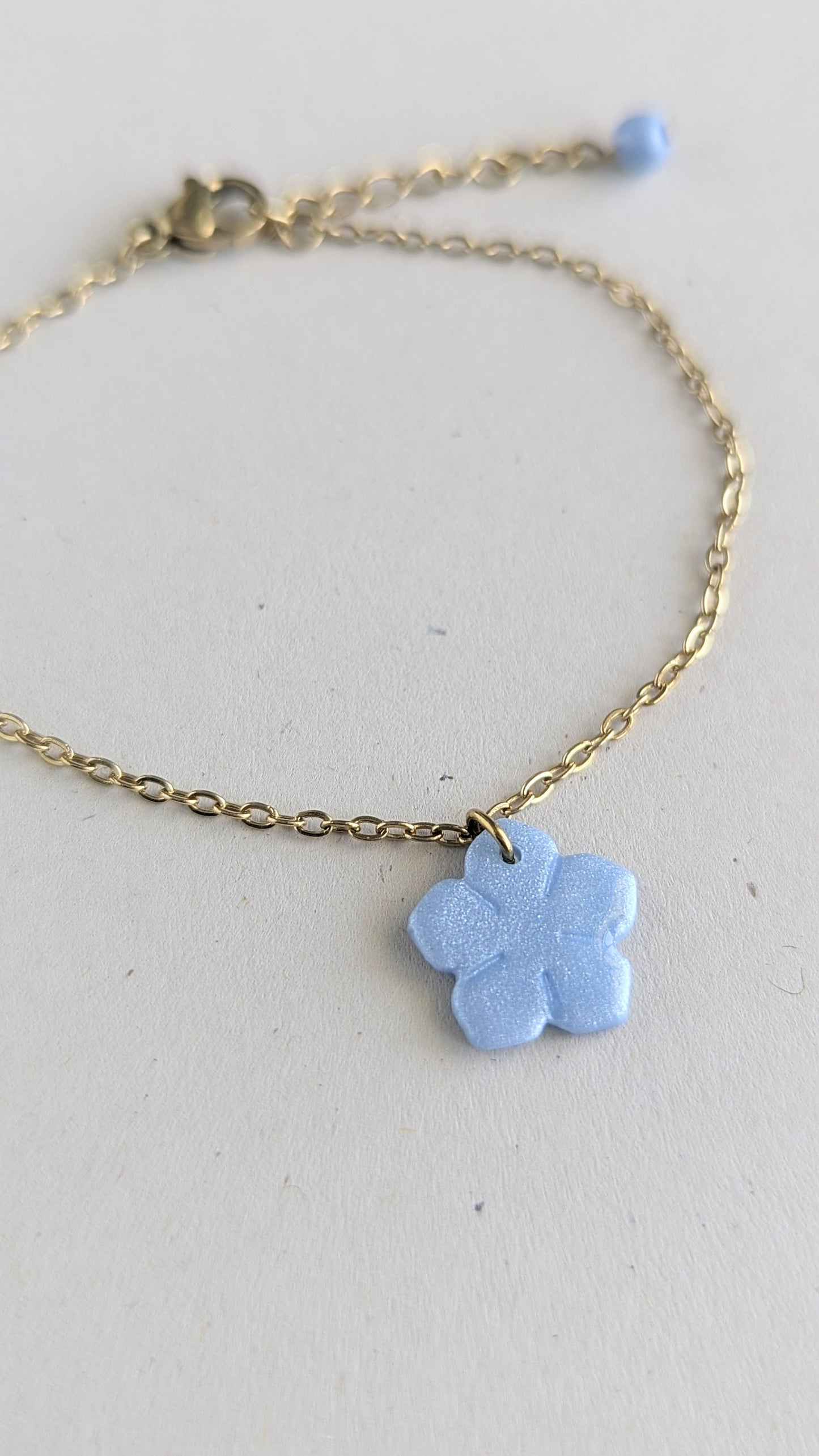 Bracelet doré pendentif fleur bleu nacrée